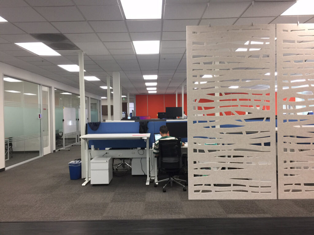 Modern Silicon Valley office collaboration lounge featuring modular seating, guest chairs, meeting tables, and glass conference rooms designed to encourage teamwork and informal meetings.