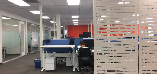 Modern Bay Area office featuring height-adjustable workstations, privacy panels, beam-mounted power, glass demountable offices, and decorative acoustic divider panels.