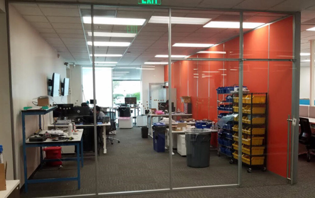 Glass demountable wall system with sliding door creating a private office within a modern Silicon Valley commercial workspace.